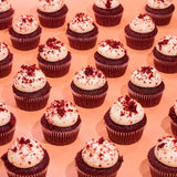 Vegan Red Velvet Cupcakes by Crumbs & Doilies with plant-based vanilla icing and red velvet crumb topping on peach background